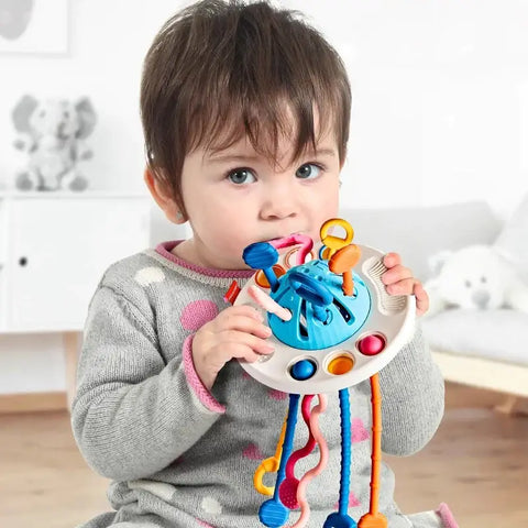 Un bébé tenant et mâchant un jouet Montessori à tirer en silicone.